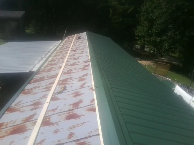 Old rusted panels beside newly installed green metal roofing — Wind Damage Roof Repair by Roofing Brothers in Apple Creek