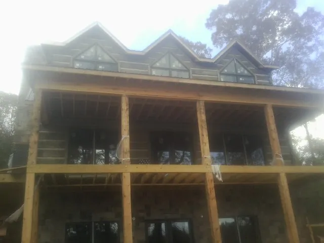 Dormers and porch framing on a large log home under construction — Roof Coating work by our crew in Apple Creek