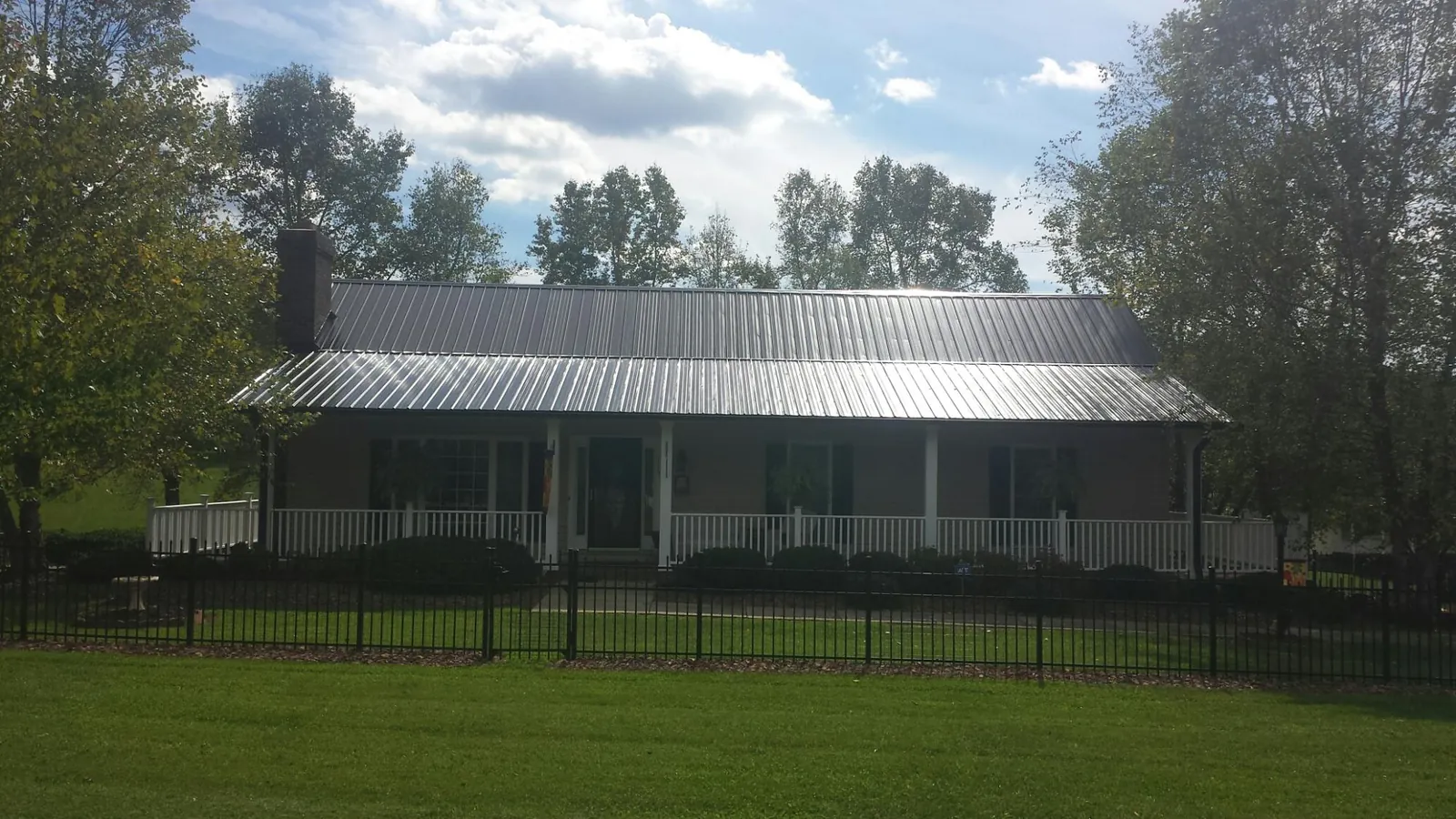 Gray metal roof on a brick ranch with a full width front porch — Gutter Guard Installation work by our crew in Apple Creek