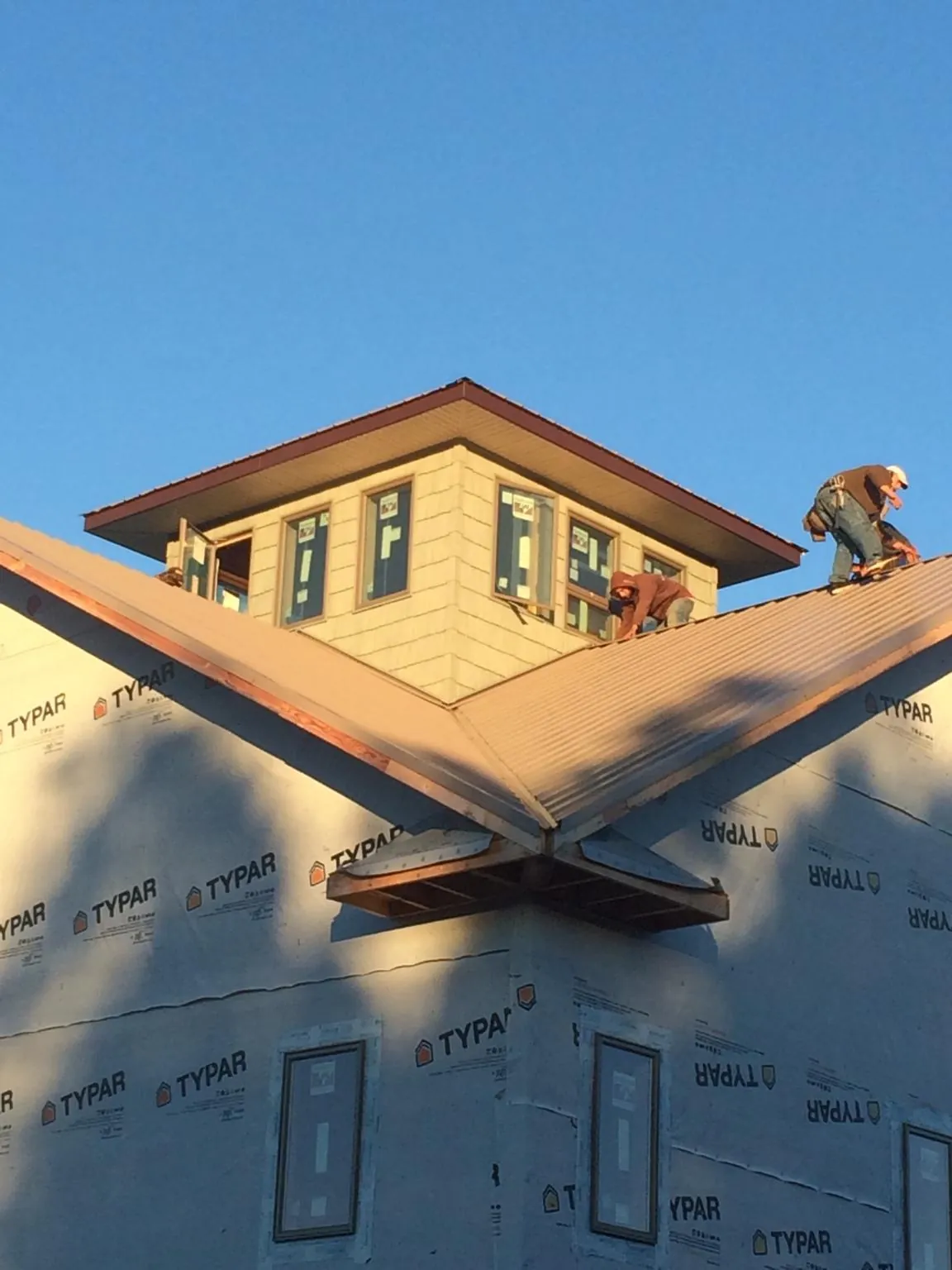 Roofers working around a rooftop cupola on a new metal roof at sunset — Roof Waterproofing in Apple Creek by Roofing Brothers